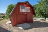 Showcasing a charming red barn with a prominent American flag displayed on its facade, this property offers a rustic and patriotic aesthetic.