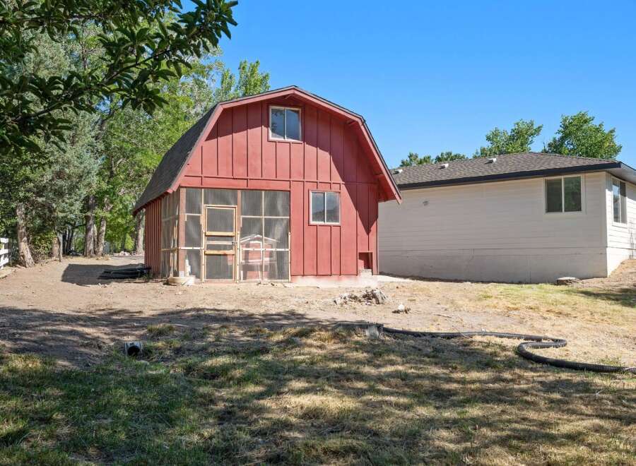 Discover this charming property featuring a unique red barn with a screened enclosure, perfect for outdoor living or animal housing.