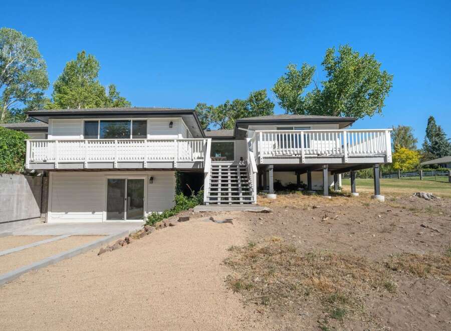 Discover this stunning multi-level home featuring expansive white decks perfect for outdoor entertaining and enjoying the scenic surroundings.