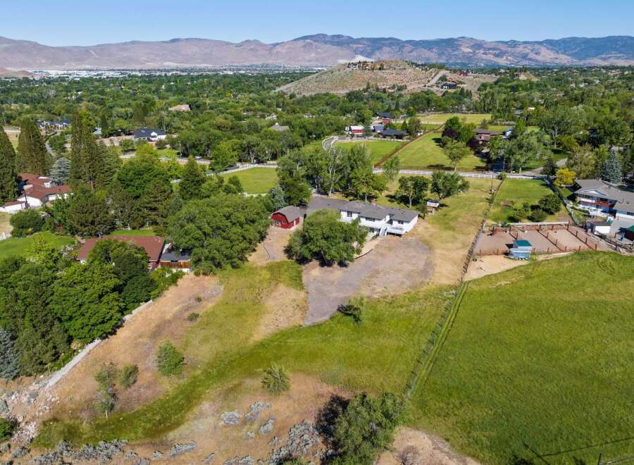 Discover this expansive property featuring a spacious main residence complemented by a charming red barn and equestrian facilities, including a riding arena and trailer.