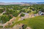 Discover this expansive property featuring a spacious main residence complemented by a charming red barn and equestrian facilities, including a riding arena and trailer.