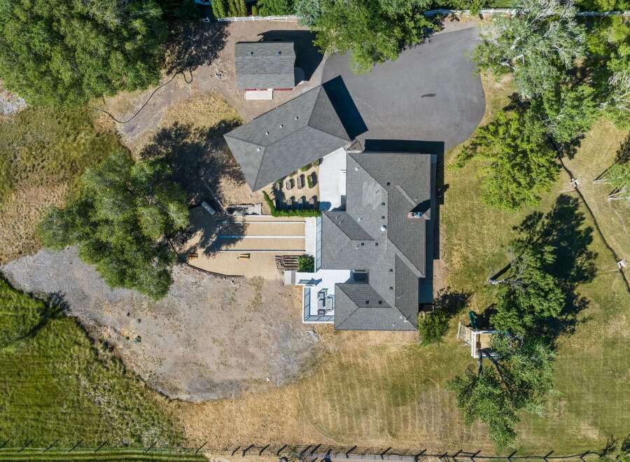 Experience luxury living in this stunning aerial view of a modern estate, featuring a sprawling main residence and a detached guest house.