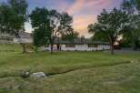 Discover this charming white ranch-style home nestled on a sprawling green lawn, perfect for outdoor enjoyment.