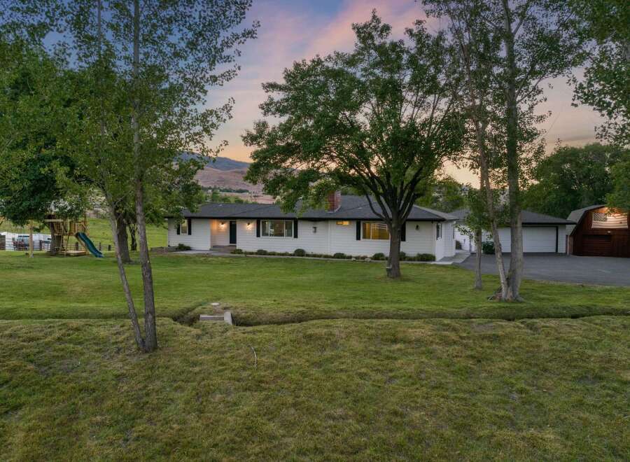 Discover this charming white ranch-style home nestled on a sprawling property, perfect for outdoor enthusiasts.