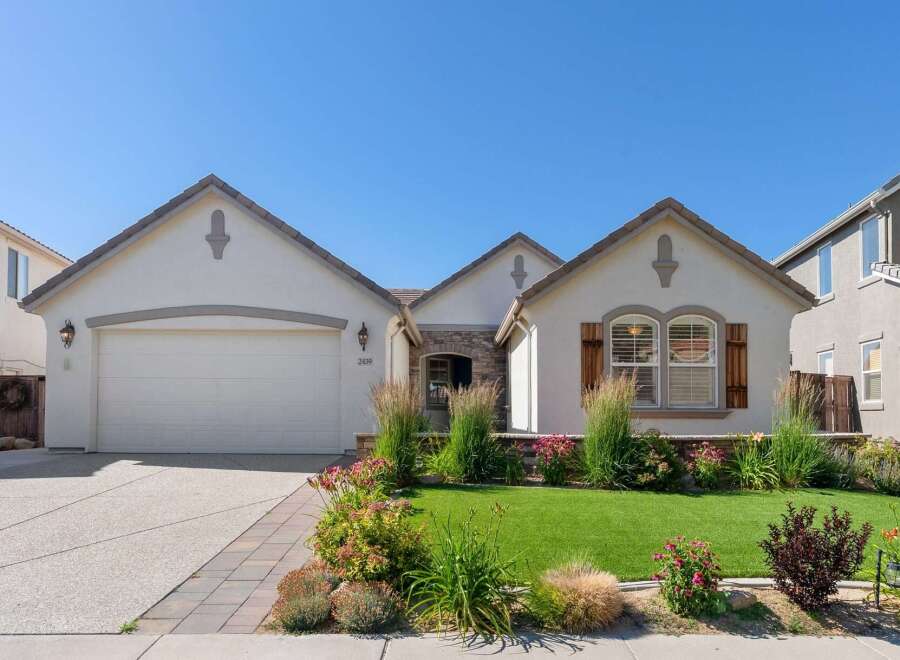 Charming single-family home featuring a well-maintained lawn and vibrant landscaping.