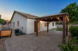 Enjoy outdoor living with this charming backyard featuring a spacious paver patio and a covered wooden pergola adorned with string lights.