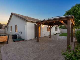 Enjoy outdoor living with this charming backyard featuring a spacious paver patio and a covered wooden pergola adorned with string lights.