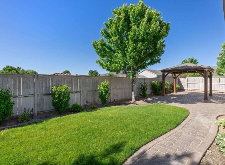 Enjoy outdoor living in this beautifully landscaped backyard featuring a spacious paver patio and a charming wooden gazebo, perfect for entertaining or relaxing.