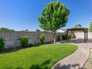 Enjoy outdoor living in this beautifully landscaped backyard featuring a spacious paver patio and a charming wooden gazebo, perfect for entertaining or relaxing.