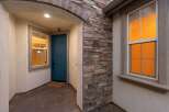 Welcome guests into this charming home through a covered entryway featuring a vibrant teal front door and a welcoming stone accent wall.