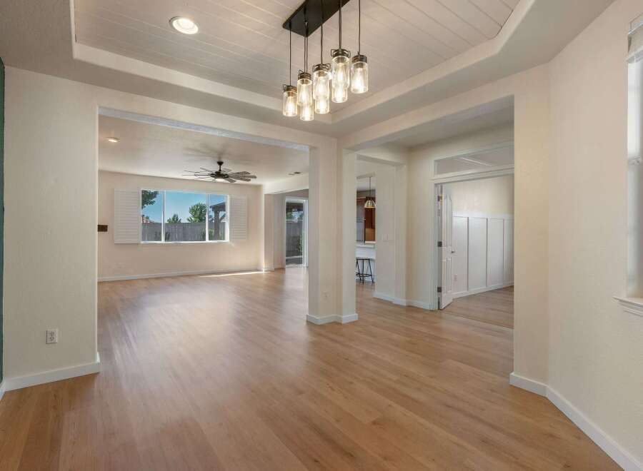 Step into this beautifully appointed living space, featuring gleaming hardwood floors and an elegant tray ceiling with recessed lighting.