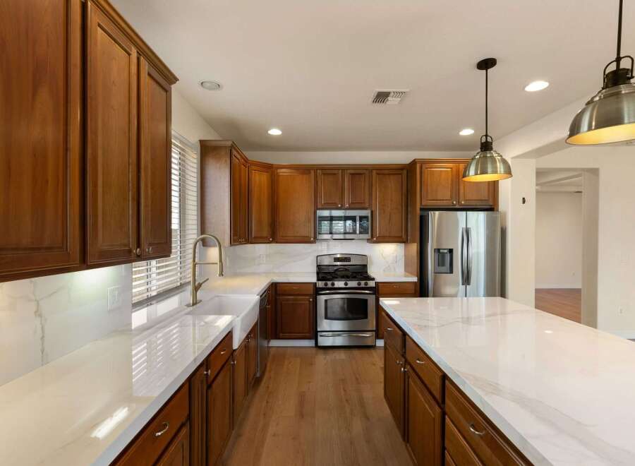 Experience luxury in this stunning kitchen featuring rich wood cabinetry and sleek marble countertops.