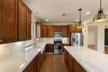 Experience luxury in this stunning kitchen featuring rich wood cabinetry and sleek marble countertops.