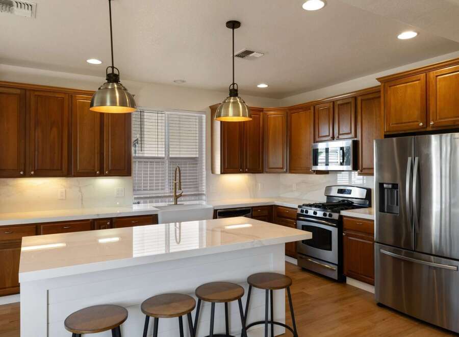Experience culinary excellence in this stunning kitchen, featuring rich wood cabinetry and a sleek white quartz island perfect for entertaining.