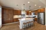 This stunning kitchen boasts rich wood cabinetry, complemented by sleek white countertops and a modern island with bar seating.