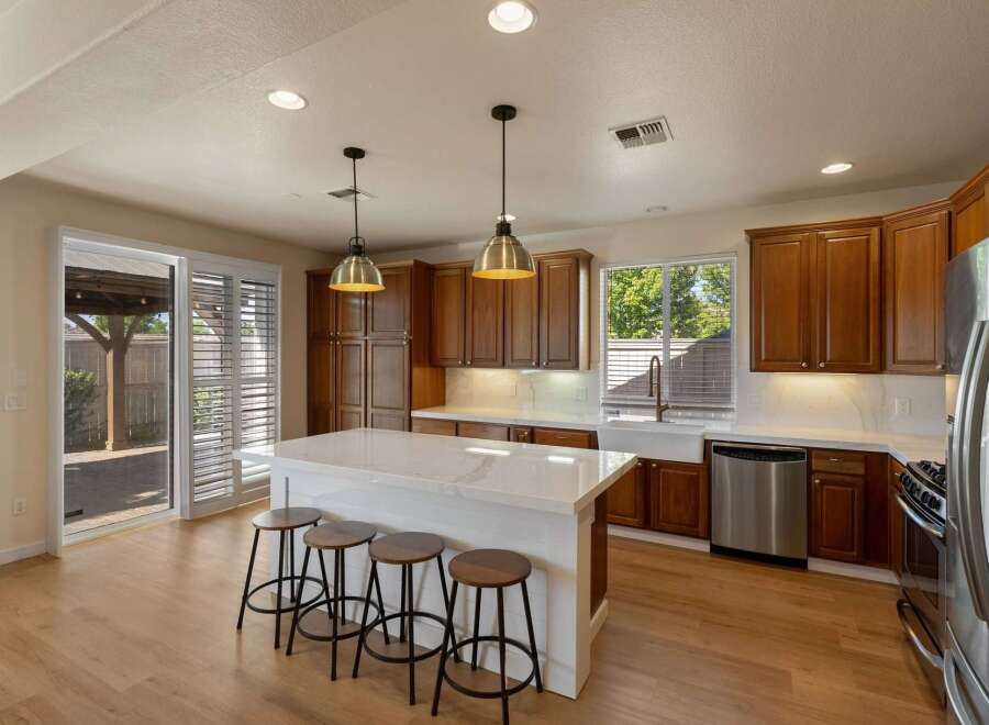 Experience the heart of this home with a stunning chef's kitchen, featuring rich wood cabinetry, a spacious quartz island with seating, and modern stainless steel appliances.