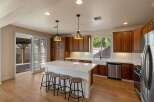 Experience the heart of this home with a stunning chef's kitchen, featuring rich wood cabinetry, a spacious quartz island with seating, and modern stainless steel appliances.