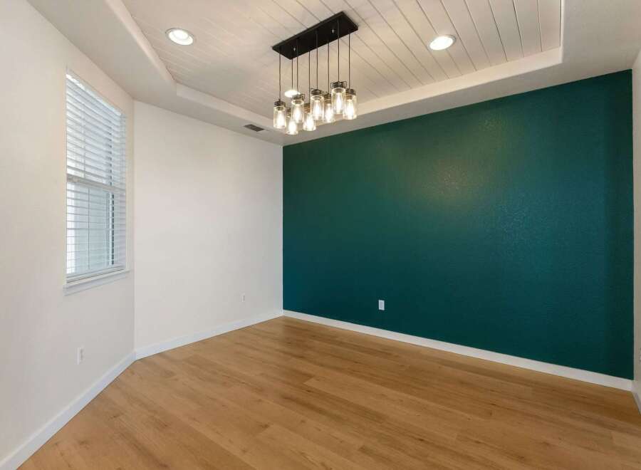 Experience modern living in this stylish dining area, featuring a striking teal accent wall that adds a pop of color and sophistication.