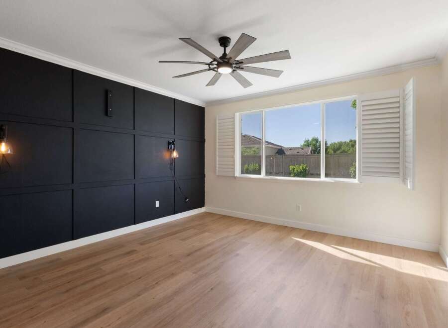 Experience modern living in this stylish room featuring a dramatic black accent wall with geometric paneling and elegant sconce lighting.