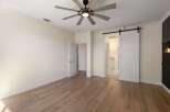 Experience modern living in this spacious bedroom featuring elegant wood-look flooring and a stylish ceiling fan.