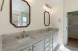 This elegant bathroom features a spacious double vanity with a stunning marble countertop and modern brass fixtures.