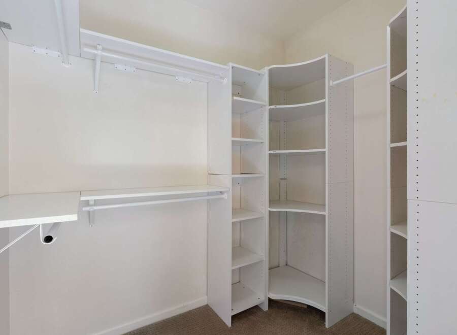 Discover ample storage in this spacious walk-in closet, featuring a versatile shelving system and multiple hanging rods.