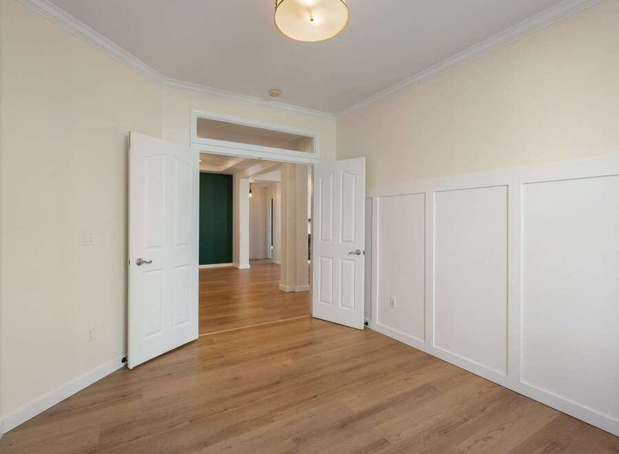 Step into this inviting space featuring elegant double doors that open to reveal a hallway with a striking dark green accent wall.