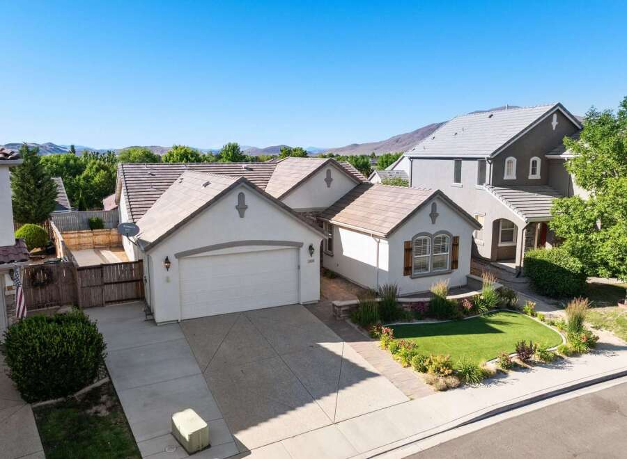 Discover this charming single-family home featuring a spacious two-car garage and a beautifully landscaped front yard with vibrant flowers and lush green grass.