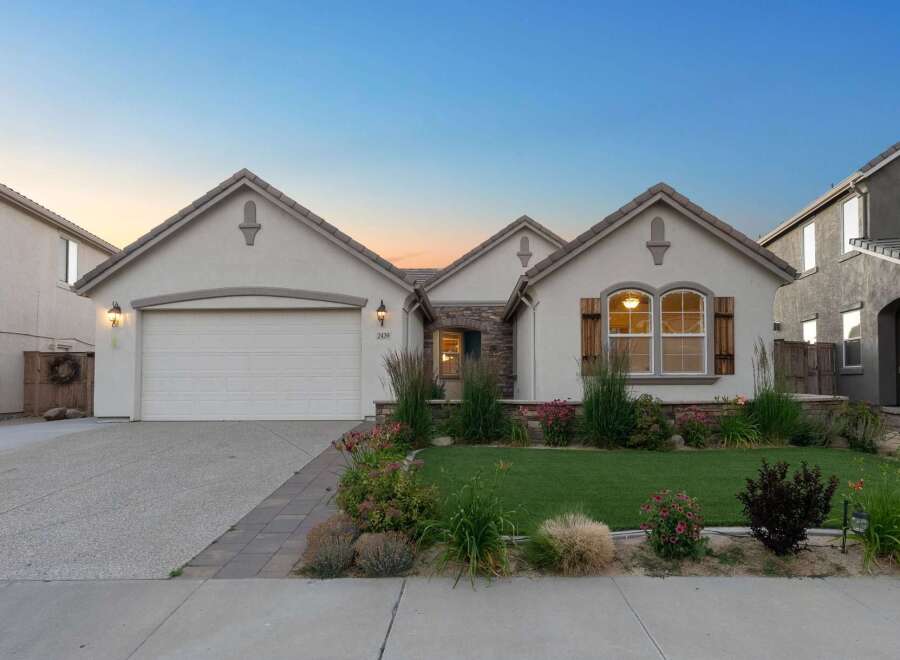 This charming single-story home features a welcoming facade with a stone-accented entrance and a spacious two-car garage.