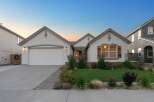 This charming single-story home features a welcoming facade with a stone-accented entrance and a spacious two-car garage.
