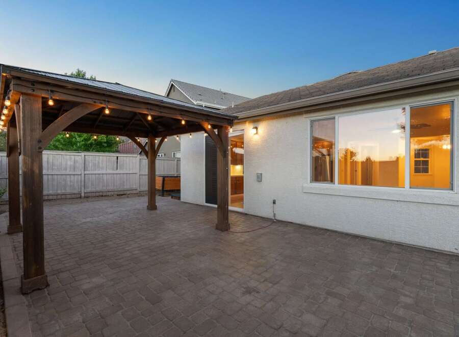 Enjoy outdoor living under this charming wooden pergola, complete with string lights for evening ambiance.