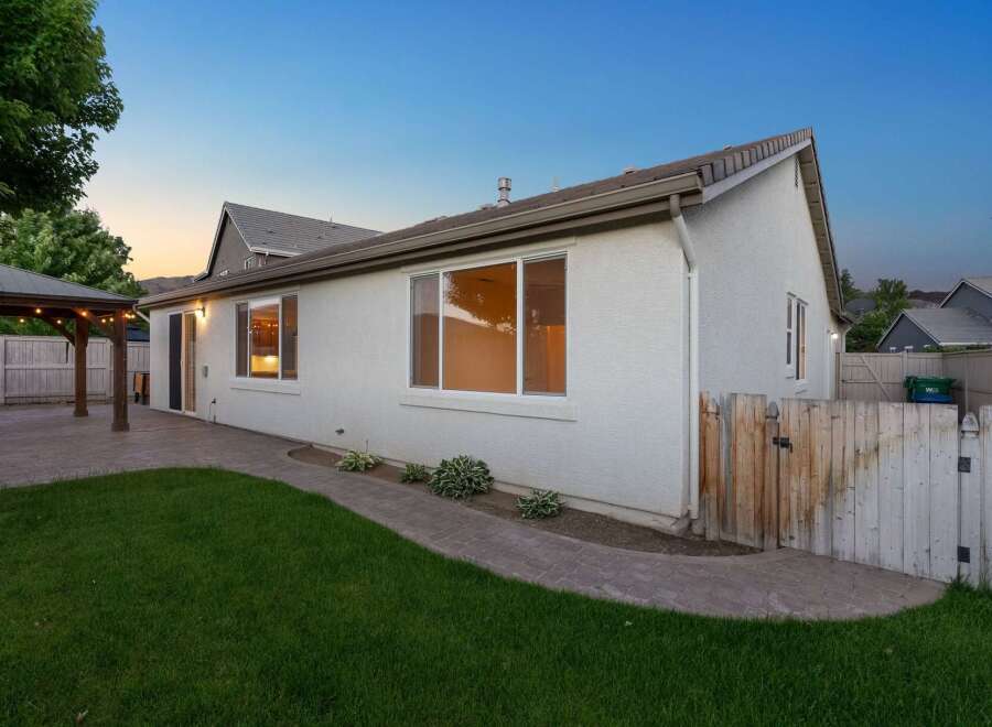 Enjoy outdoor living in this charming backyard featuring a covered patio with string lights, perfect for entertaining.