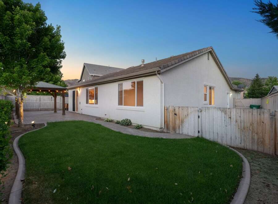 Enjoy evenings in this charming backyard featuring a covered patio with string lights, perfect for outdoor dining and entertaining.