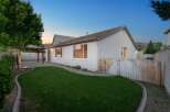 Enjoy evenings in this charming backyard featuring a covered patio with string lights, perfect for outdoor dining and entertaining.