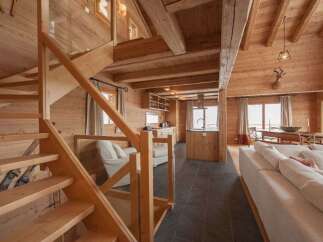 Experience rustic charm in this stunning wooden chalet, featuring a grand staircase leading to an open-plan living area.