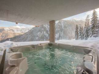 Experience ultimate relaxation in this luxurious outdoor hot tub, perfectly situated to offer breathtaking panoramic views of snow-capped mountains and evergreen forests.