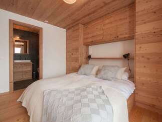 Experience rustic charm in this beautifully appointed bedroom featuring warm, natural wood paneling throughout the walls and ceiling.