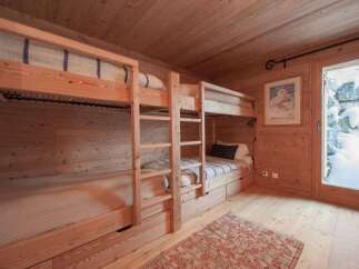 Experience cozy mountain living in this charming wooden cabin bedroom, featuring a space-saving bunk bed setup with ample storage drawers.