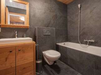Experience modern comfort in this stylish bathroom, featuring a sleek vessel sink atop a warm wooden vanity.