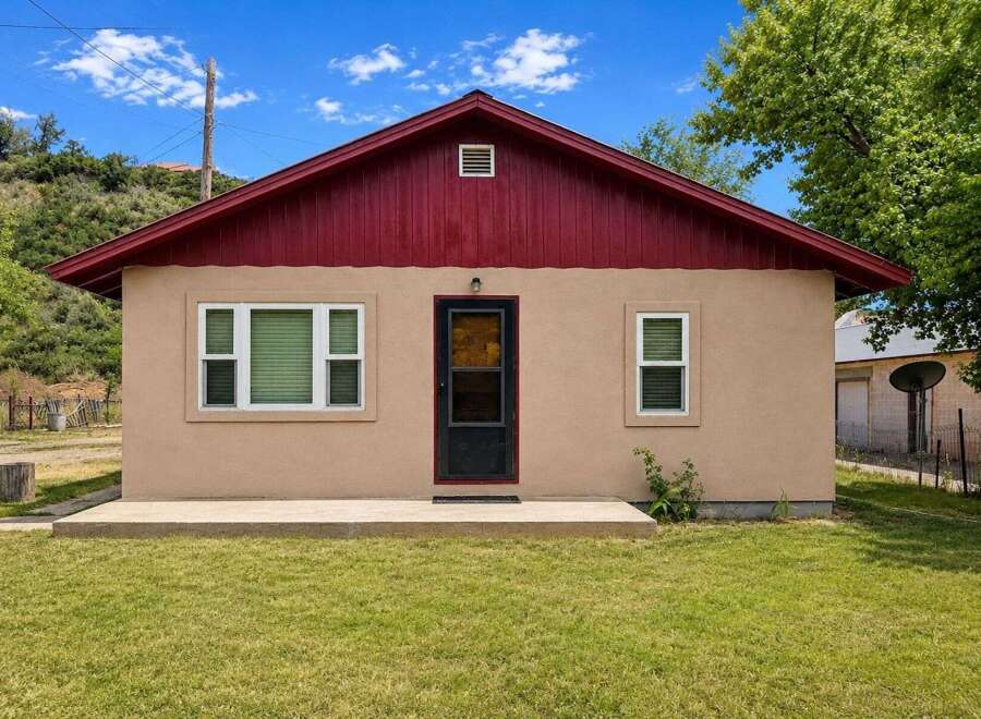 Charming single-story home featuring a welcoming beige exterior and a vibrant red roof.