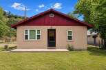 Charming single-story home featuring a welcoming beige exterior and a vibrant red roof.
