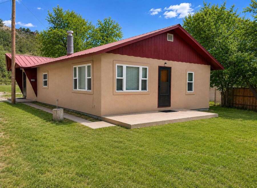 Charming single-story home with a durable metal roof and a welcoming tan stucco exterior.