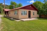 Charming single-story home with a durable metal roof and a welcoming tan stucco exterior.