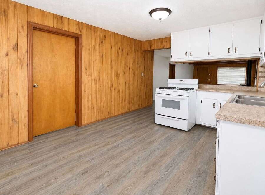This charming kitchen features warm wood-paneled walls and a durable, modern vinyl plank floor.
