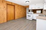 This charming kitchen features warm wood-paneled walls and a durable, modern vinyl plank floor.