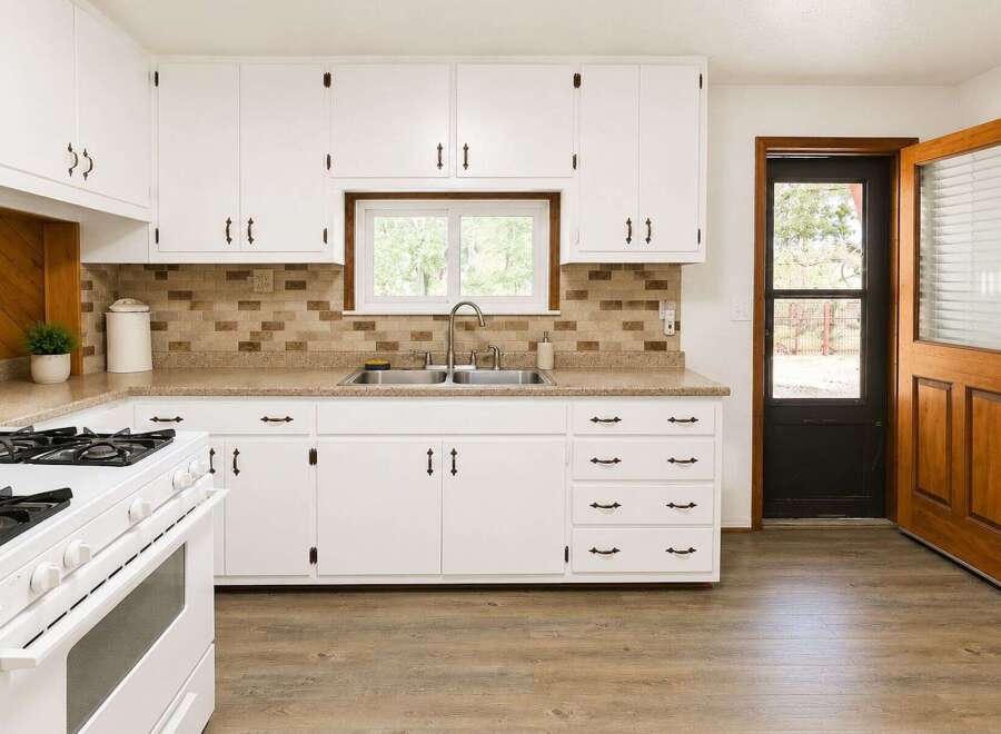 Discover this charming kitchen featuring crisp white cabinetry and a stylish tile backsplash.