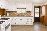 Discover this charming kitchen featuring crisp white cabinetry and a stylish tile backsplash.