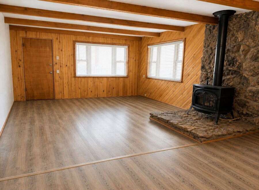 Experience rustic charm in this inviting living space, featuring warm wood paneling and exposed ceiling beams.