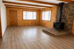 Experience rustic charm in this inviting living space, featuring warm wood paneling and exposed ceiling beams.