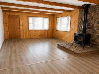 Experience rustic charm in this inviting living space, featuring warm wood paneling and exposed ceiling beams.